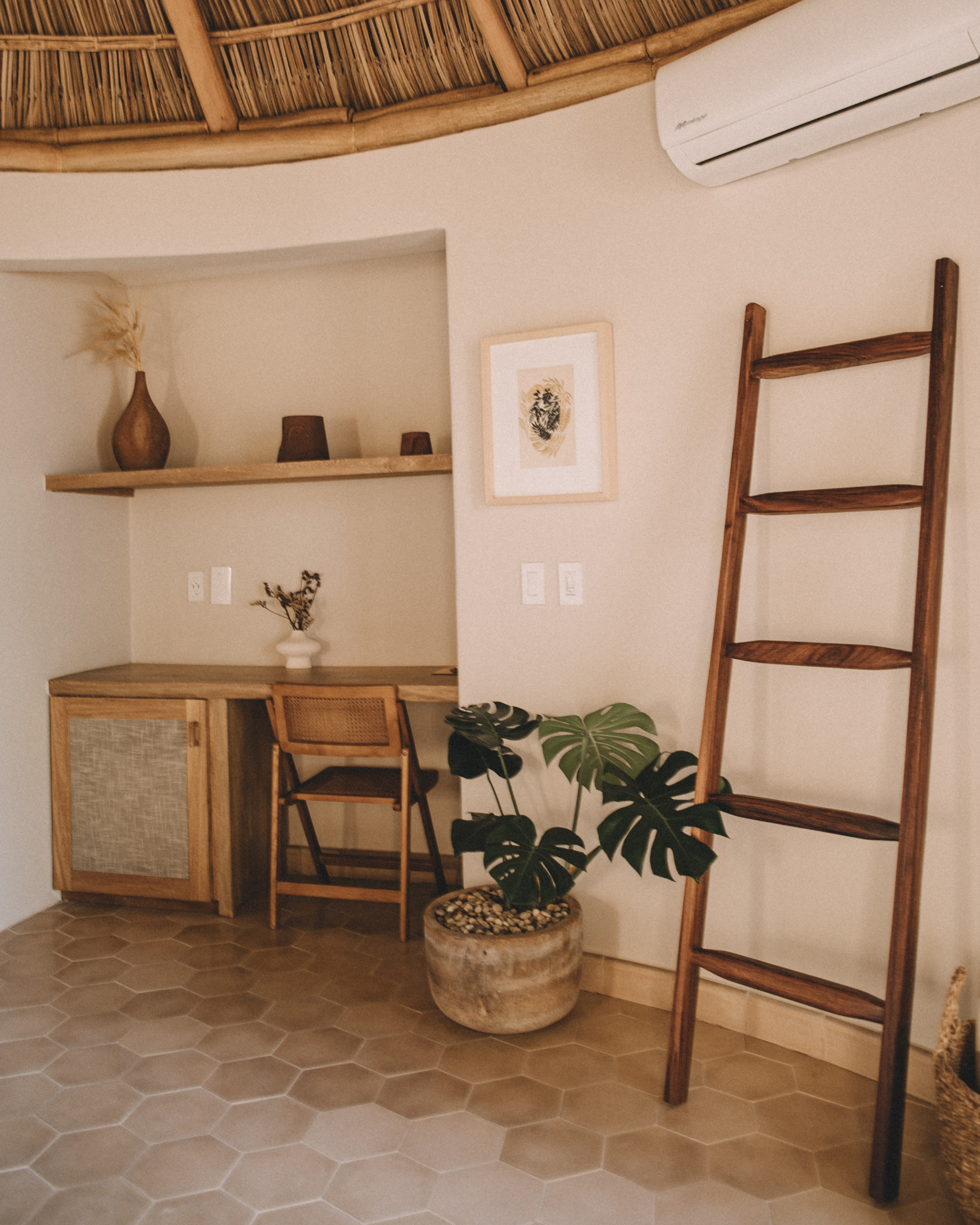 Bungalow interior detail with desk, monstera plant and wooden ladder